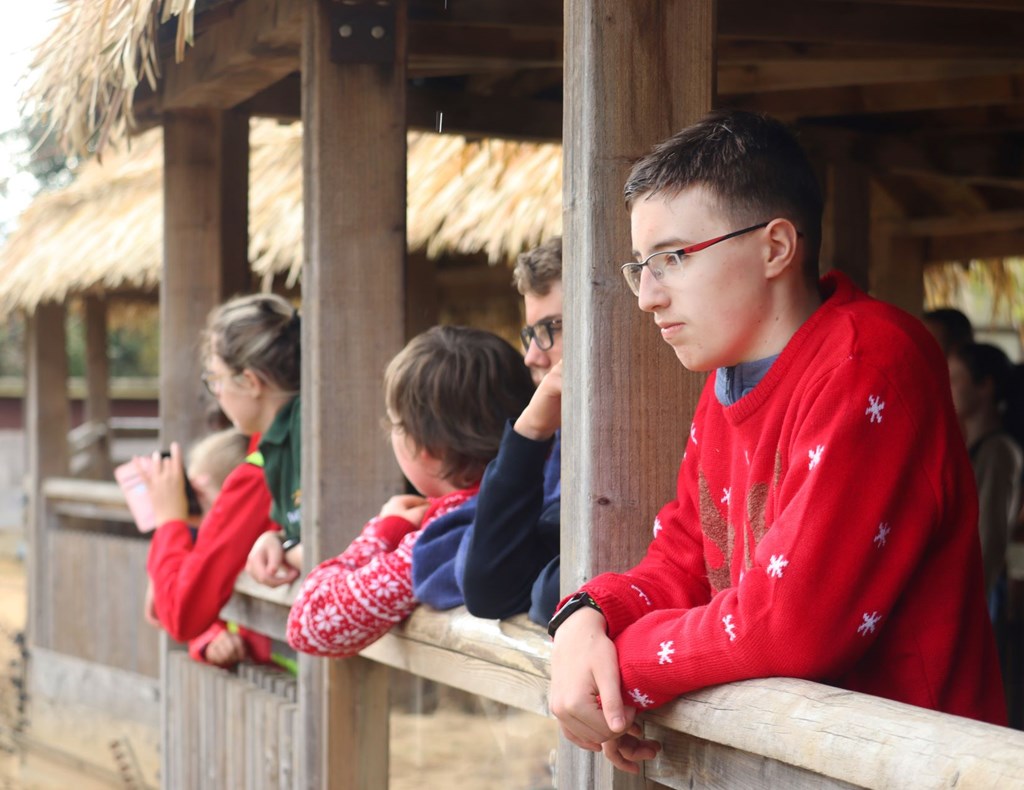 Teenagers in christmas jumpers look out onto meerkat enclosure 