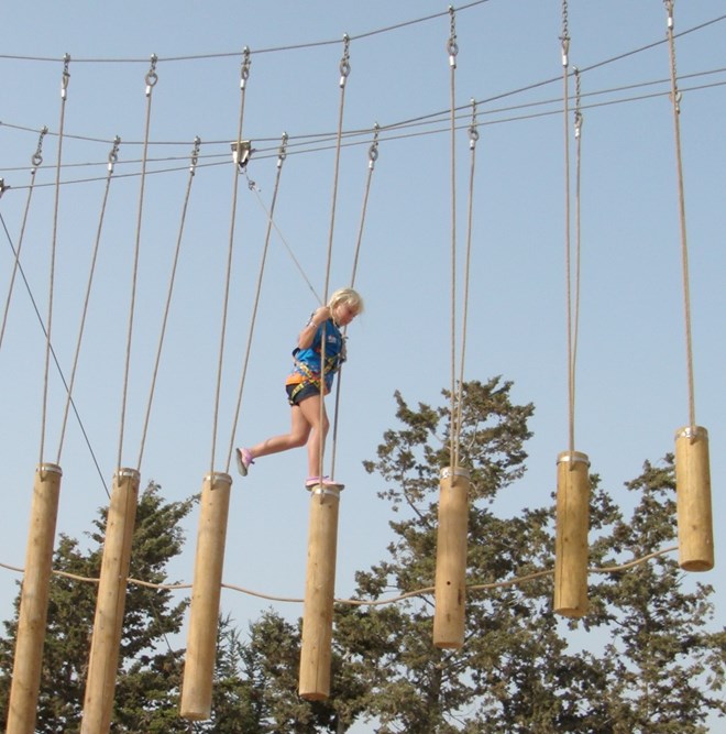 Child walks across beams in high ropes course