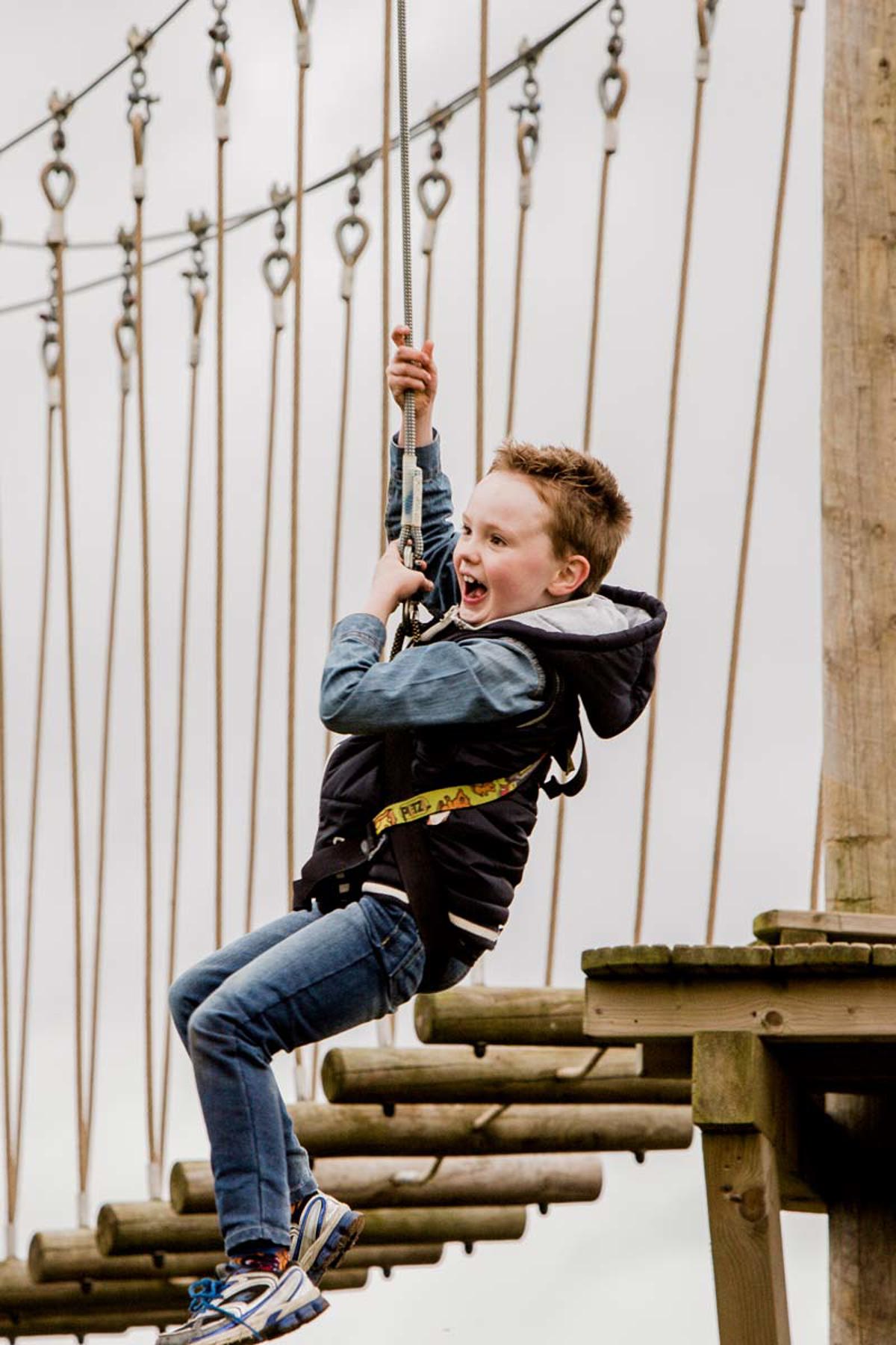 Child screams happily while ziplining on high ropes course
