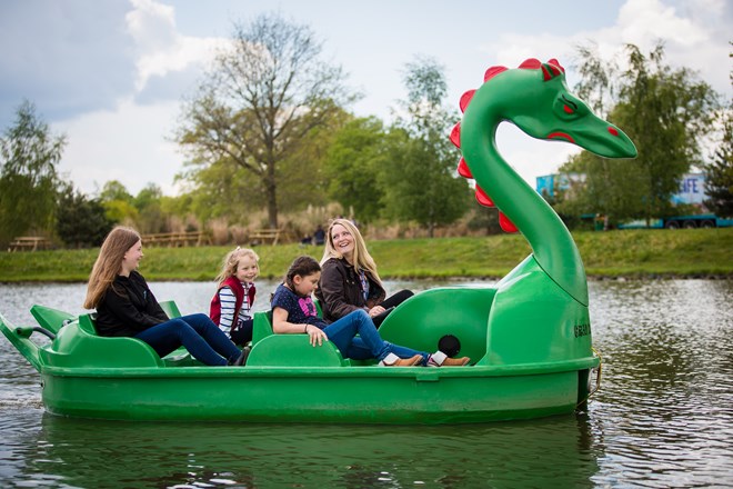 Family enjoy a ride on green dragon pedlo boat on lake 