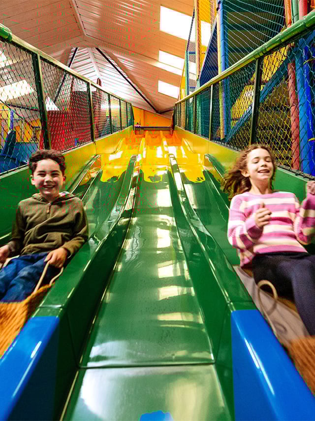 Two children going down the slide inside the Mammoth Play Ark, indoor soft play