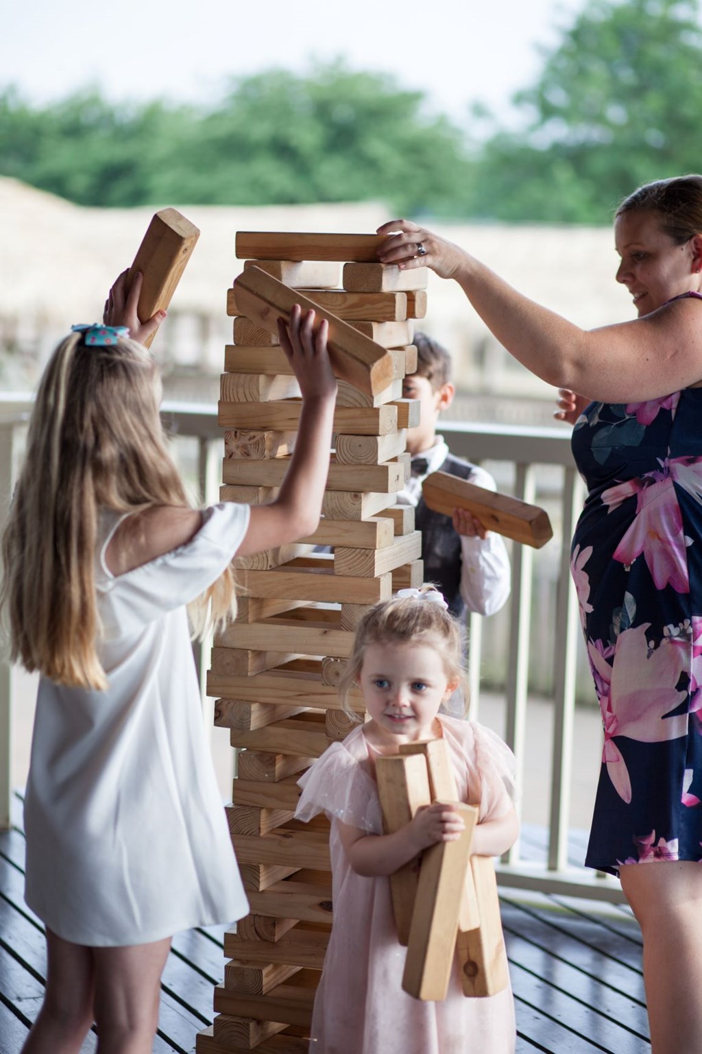 Three children and one woman play giant Jenga on the deck of the Safari Lodge